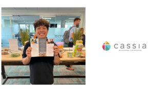 Devon, the Diversity and Inclusion Intern at Cassia, smiles while holding a brochure during his farewell gathering at the Cassia Home Office, surrounded by snacks and drinks. The staff celebrated Devon's impactful contributions to promoting inclusivity within the community as he prepares to head off to school.