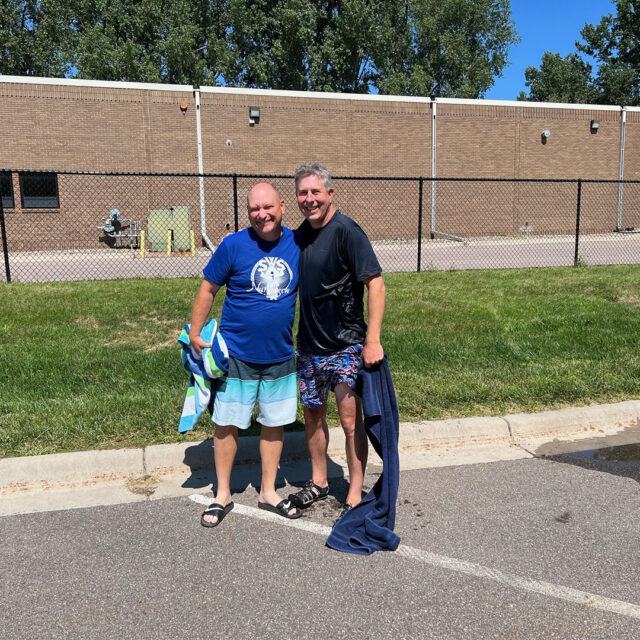 Two Cassia employees smile together, one holding a towel after participating in the dunk tank event, while the other is preparing to take their turn at the State Fair-inspired picnic.