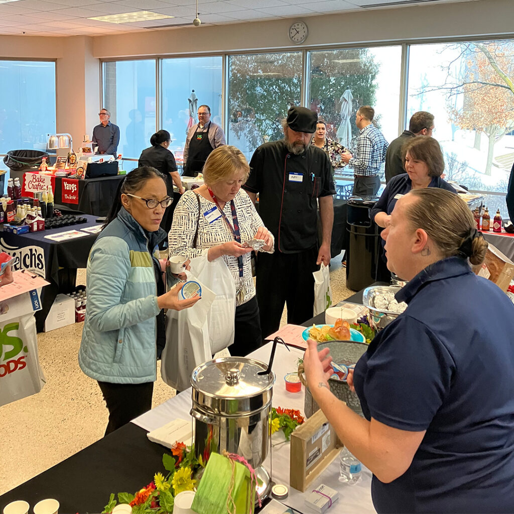 Cassia culinary team members evaluate and discuss food samples at a vendor booth during the Cassia food show, collaborating to enhance residents' dining experiences.