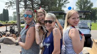 Alt text: Staff showing temporary Bob Dahl tattoos at the Milaca Elim Meadows Golf Classic.