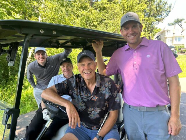 Four golfers smiling together next to a golf cart during the 2025 Cassia Golf Tournament.