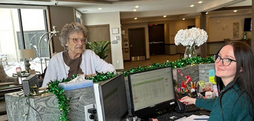 Karina, the receptionist at the Meadowview of Davenport, assists a resident and greets visitors in the community lobby.