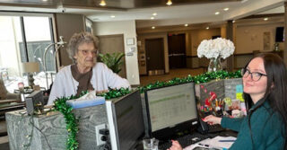 Karina, the receptionist at the Meadowview of Davenport, assists a resident and greets visitors in the community lobby.