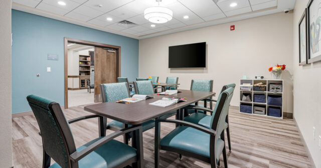 Memory care activity room at Meadowview of Johnston with table, chairs, coloring materials and a TV for resident programming