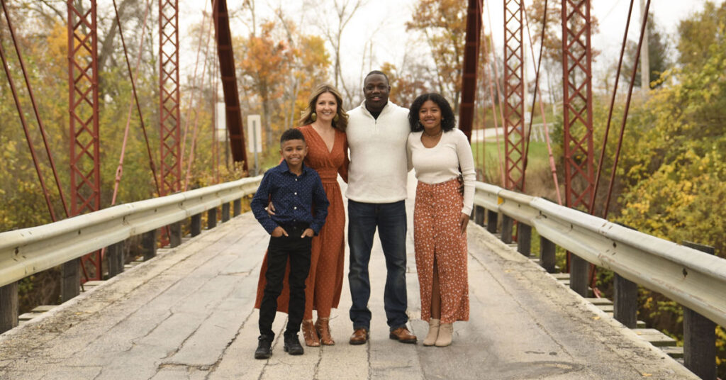 Group of four standing on a pedestrian bridge surrounded by fall foliage