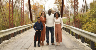 Group of four standing on a pedestrian bridge surrounded by fall foliage