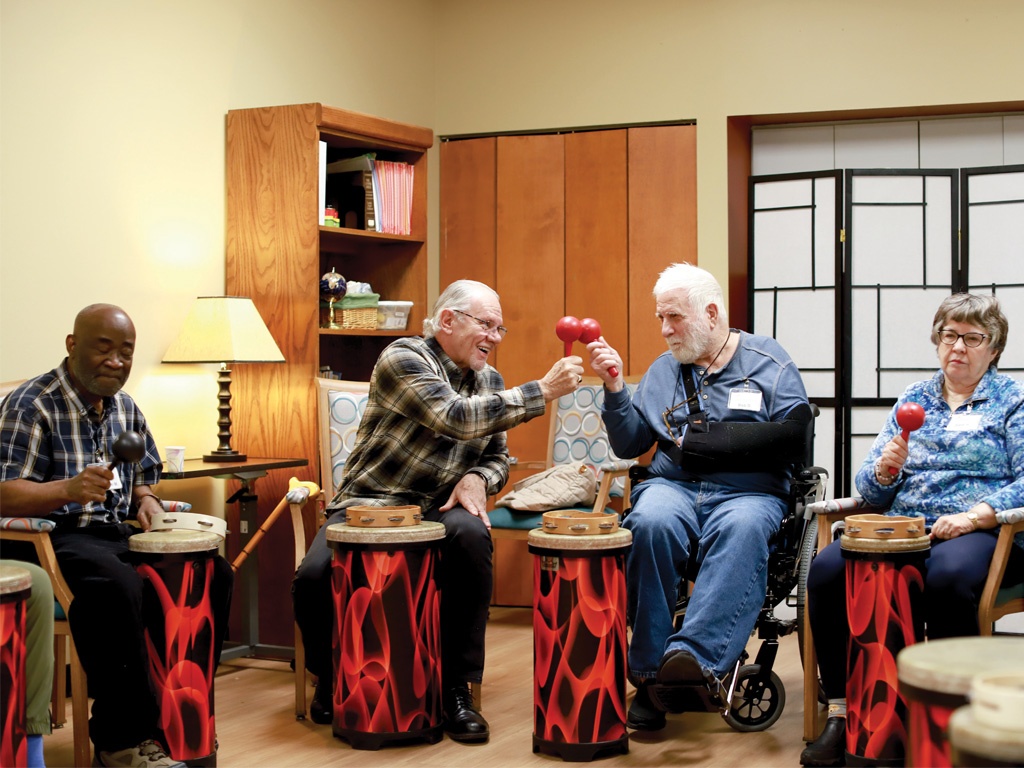 Adults in a dementia arts program use drums and maracas during a group music session at Open Circle, encouraging social connection, rhythm, and engagement