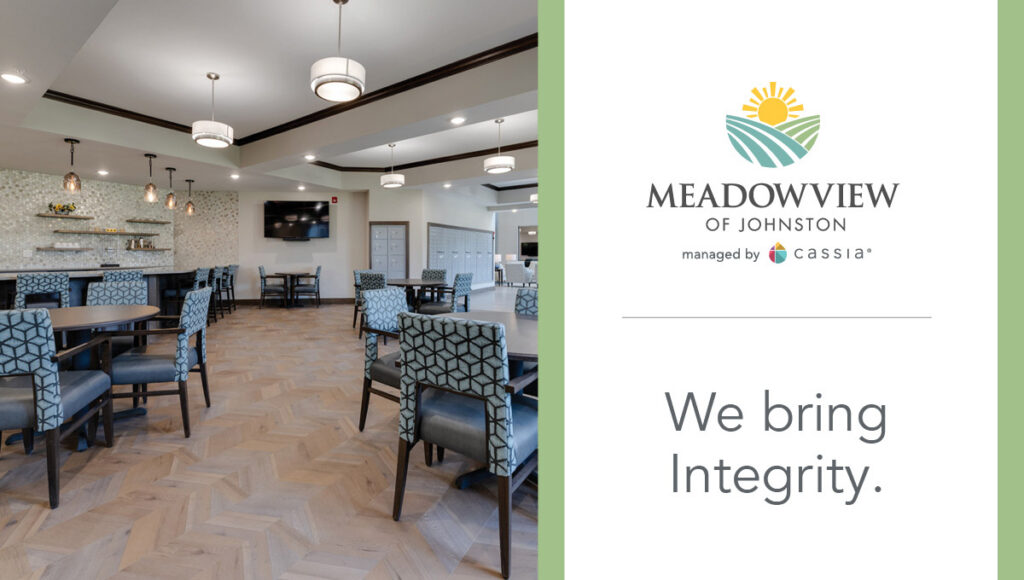 Interior common area at Meadowview of Johnston featuring dining tables, upholstered chairs, a bar seating area, and a television in a bright, modern senior living community. Branding on the image reads “Meadowview of Johnston” and “We bring Integrity.”