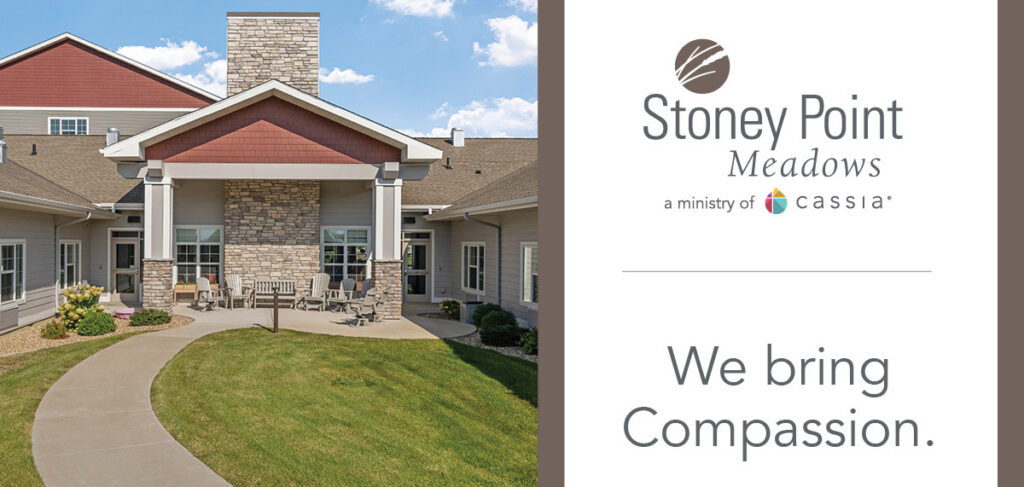 Exterior view of Stoney Point Meadows senior living community in Cedar Rapids, featuring landscaped grounds, walking path, and main entrance with seating area.