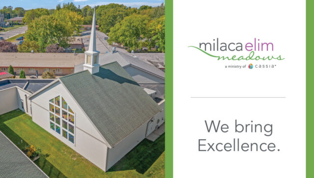 Aerial view of the chapel at Milaca Elim Meadows, featuring a steep roof, white steeple, and large stained-glass window, surrounded by green lawns and trees, alongside branding that reads “Milaca Elim Meadows” and “We bring Excellence.”