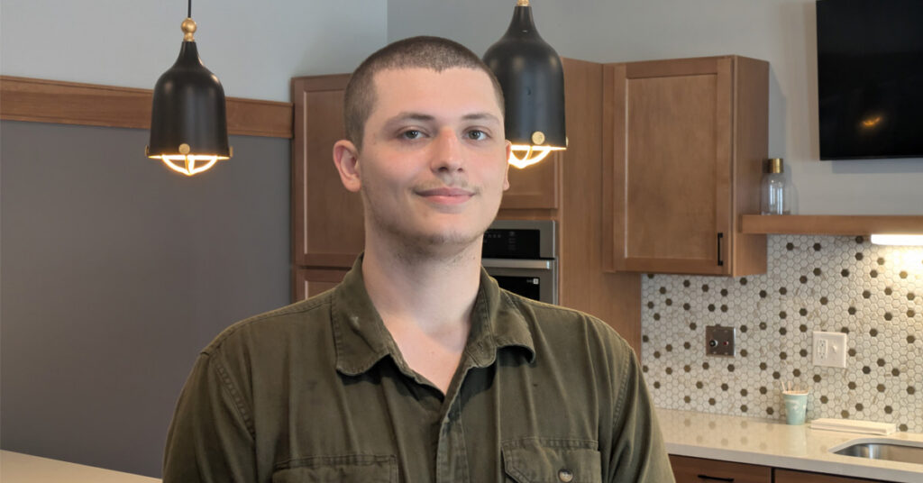 Chris, Culinary Director at Harmony Gardens, pictured in a bright community common area with cabinetry, countertops, and pendant lighting.