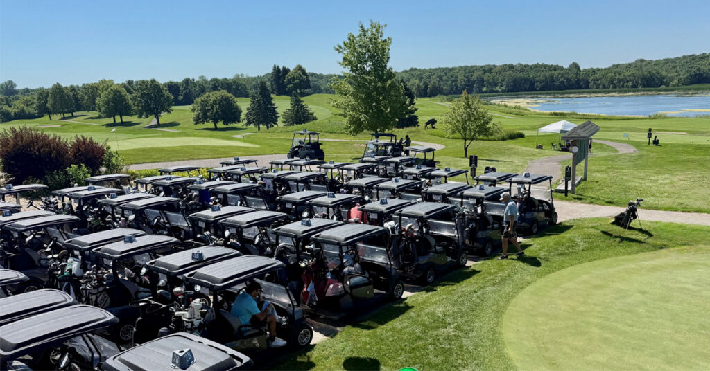 Rows of golf carts lined up at a golf course beside a lake during the Community Health Foundation of Wright County Golf Tournament in Buffalo, Minnesota.