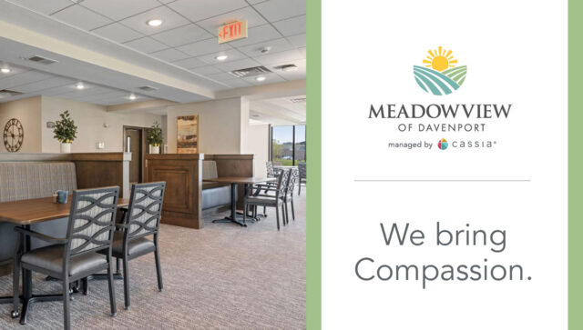 Meadowview of Davenport’s dining room features comfortable seating, wood accents, and large windows, alongside the community logo and the message, “We bring Compassion.”