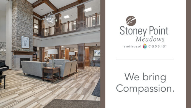 Stoney Point Meadows senior living community lobby with a stone fireplace, wood accents, comfortable seating, and the message: “We bring Compassion.”
