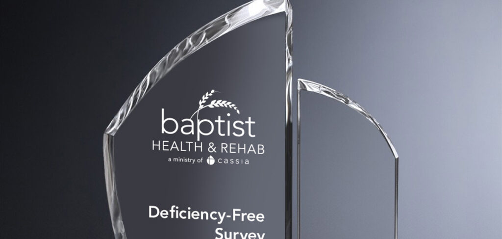 Crystal award engraved with “Baptist Health & Rehab” and “Deficiency-Free Survey” against a gray gradient background.